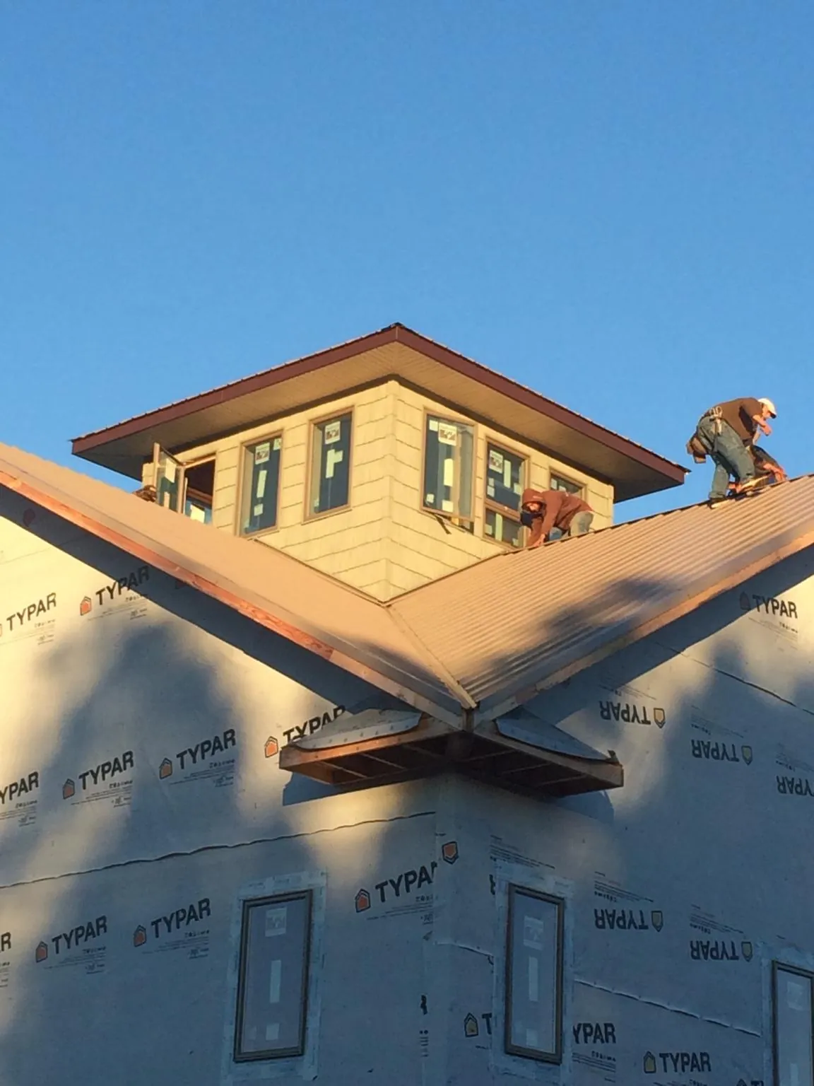 Roofers working around a rooftop cupola on a new metal roof at sunset — Roof Waterproofing in Bear Creek by Roofing Brothers